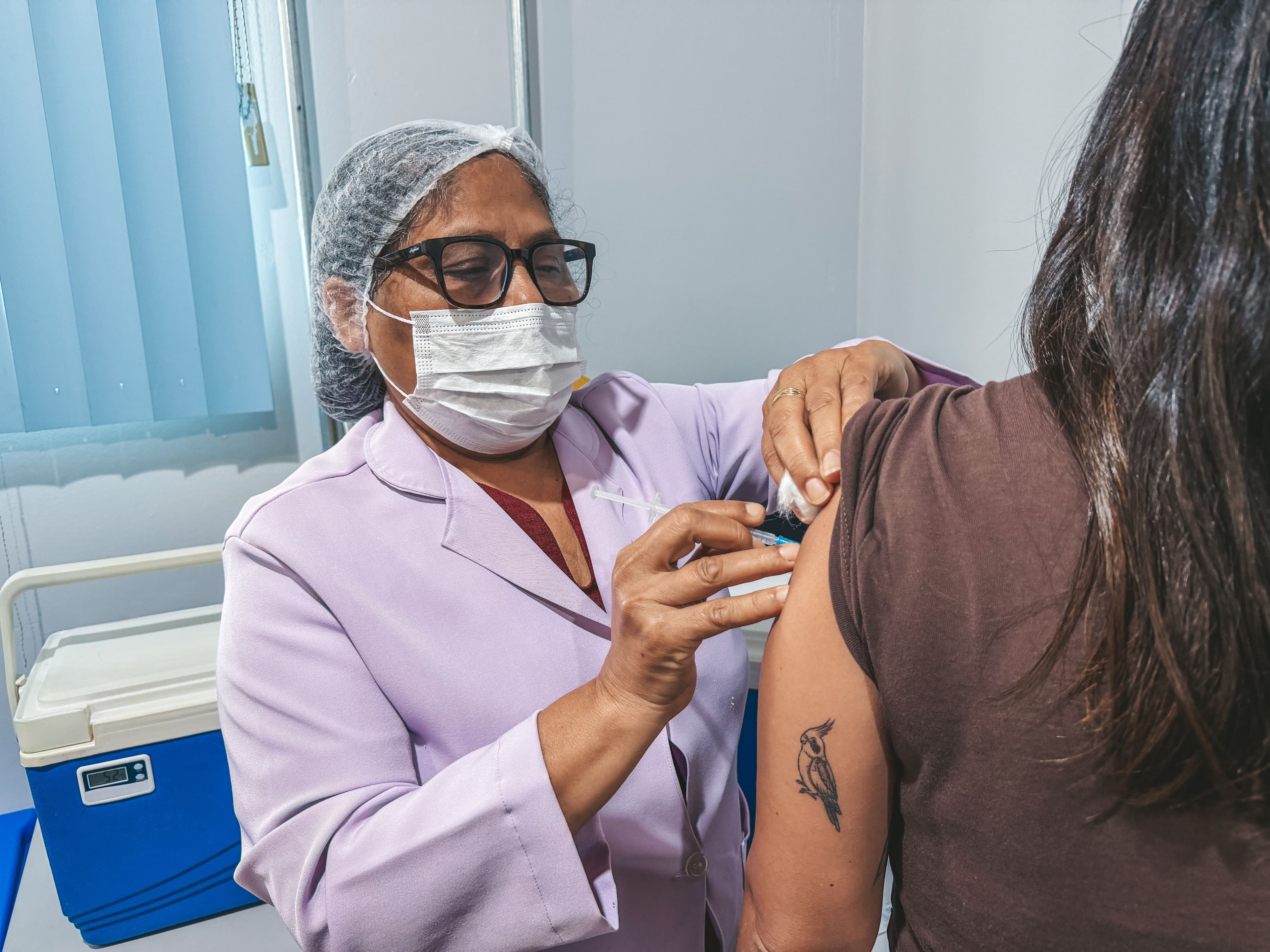 Profissional de saúde durante atendimento de vacinação em unidade pública.